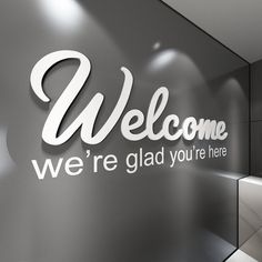 a welcome sign on the side of a glass wall in front of a mirror door