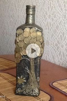 a bottle filled with lots of coins sitting on top of a wooden table next to a wall