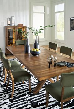 a dining room table with green chairs and black and white area rug on the floor