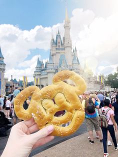 a person holding up a pretzel in front of a castle