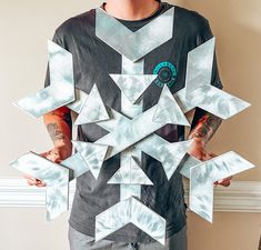 a man standing in front of a wall holding up a cut out paper snowflake