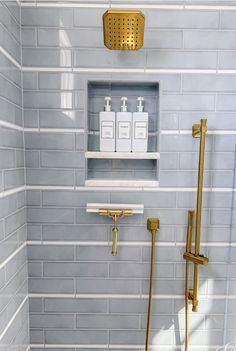 a bathroom with gray tile and gold fixtures in the shower area, along with toiletries