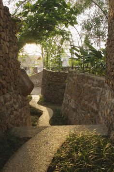 an alley way between two stone buildings with trees in the backgrouds and grass on either side