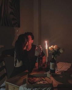 a man and woman sitting at a table in front of a pizza with a lit candle