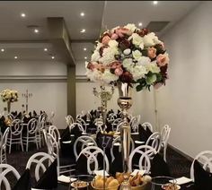 an elegantly decorated banquet hall with white chairs and black table cloths, flowers in centerpiece