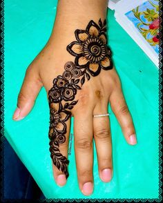 a woman's hand with henna tattoos on her left hand and flowers on the wrist