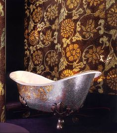 an ornate bathtub sits in front of a wall with gold and silver designs on it