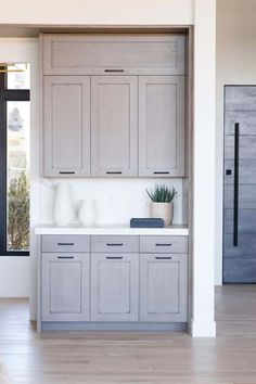 an empty kitchen with gray cabinets and white counter tops is seen in this image from the doorway