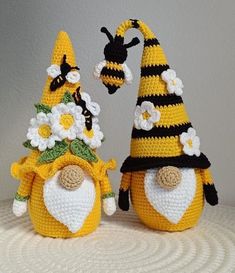 two crocheted bees with hats and flowers