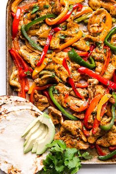 chicken fajita with peppers and cilantro on a tray next to tortillas