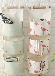 three pockets hanging from the wall with flamingos on them and one pocket for pens