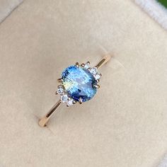 an oval shaped blue and white diamond ring in a box with the lid open to show it's inside