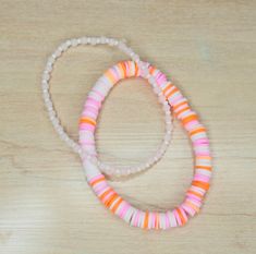 two bracelets on a wooden table with beads and plastic bead around the wrist