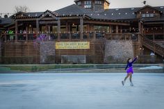 a woman is playing tennis in front of a large building with lights strung from the roof