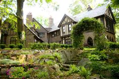 a large house surrounded by lush green trees and flowers in front of it's entrance