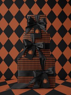 a stack of black and orange boxes with pumpkins on them sitting in front of a checkered wall