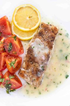 a white plate topped with fish and tomatoes