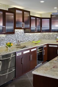 a modern kitchen with stainless steel appliances and marble counter tops, along with dark wood cabinets