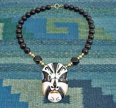 Chinese Porcelain Peking Opera Mask Onyx Necklace This necklace is dramatic.  The pendant is made from porcelain and the design on the pendant is enhanced by the large black heavy onyx and gold colored beads.   The mask has Chinese markings on the back.  The pendant measures 3 1/2" long by 2 1/5" wide.  The necklace measures 20 1/2" long.  The black onyx beads are 14 mm and the two octagonal onyx beads measure 18 mm.  This comes with a gift box.  Shipping is free on this item to addresses within Peking Opera Mask, Opera Mask, Peking Opera, Bohemian Grunge, Grunge Jewelry, Mask Necklace, Blue Tassel, Onyx Necklace, Onyx Bead