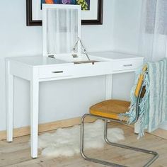 a white desk with a mirror, chair and rug in front of it on the floor