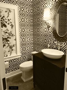 a black and white photo of a bathroom with wallpaper on the walls, toilet and sink