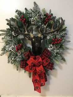 a deer head mounted to the side of a wall with pine cones and evergreens