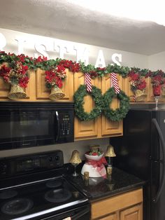 a kitchen decorated for christmas with wreaths on the wall and garland hanging over the stove