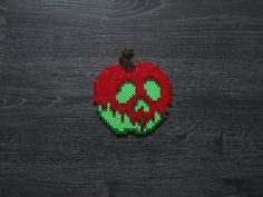 an apple with green and red paint splattered on it's face, sitting on a wooden surface