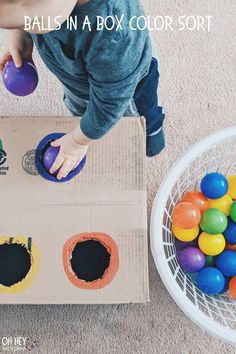 a child playing with balls in a box