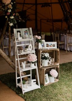 an outdoor wedding setup with flowers and pictures on the shelves in front of the tent