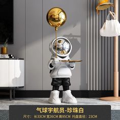 a white and gold robot holding a tray with a golden ball on it's head