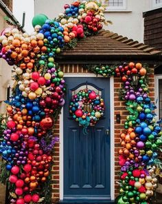 a blue door decorated with christmas ornaments and balloons in front of a brick house that has a wreath on it