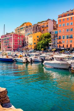 many boats are docked in the water next to some colorful buildings and trees on either side