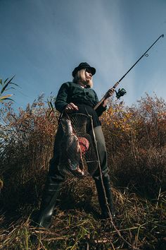 a man standing in the grass holding a fishing pole