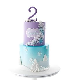 a three tiered cake with snowflakes on it and the number two on top