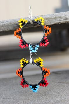 a pair of multicolored beaded hoop earrings hanging from a wooden bench