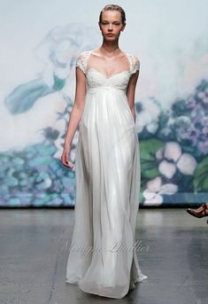 a woman is walking down the runway wearing a white dress with sheer shoulders and an open back