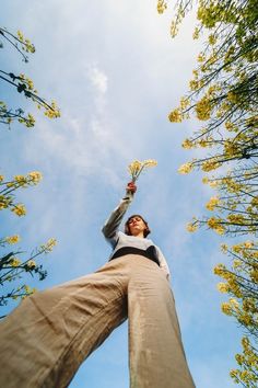 a man reaching up into the sky with his hands in the air while standing between two tall trees