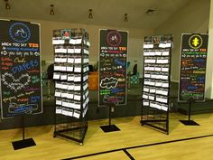 three blackboard displays with writing on them in a gym floored area at the end of a basketball court