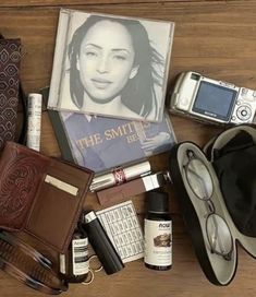 an assortment of personal items laid out on top of a wooden table next to a purse