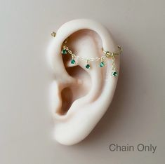 a pair of ear piercings with green beads