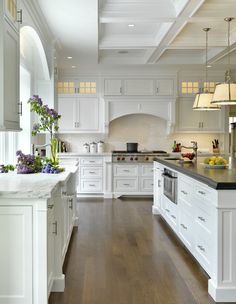 a large kitchen with white cabinets and black counter tops, along with an island in the middle