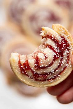 a hand holding a pastry with powdered sugar on it