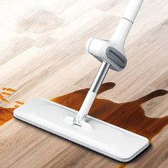 a white mop on top of a wooden floor with orange paint splatters