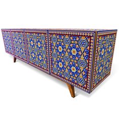 an ornately decorated sideboard with wooden legs and colorful tiles on the top, against a white background