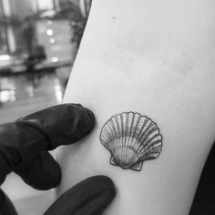 a black and white photo of a shell on the back of a woman's arm