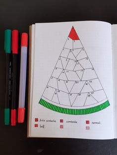 an open notebook with a christmas tree drawn on it and markers next to the pages