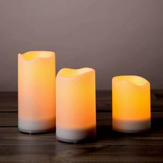 three lit candles sitting on top of a wooden table