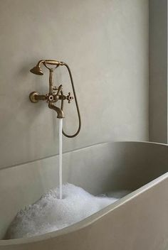 a bathtub filled with foam and water running from the faucet to the wall