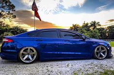 a blue car parked in front of an american flag